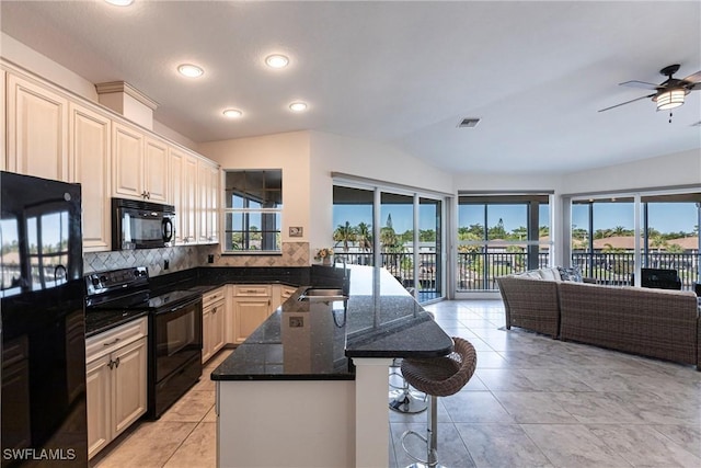 kitchen with black appliances, a breakfast bar, open floor plan, a peninsula, and decorative backsplash