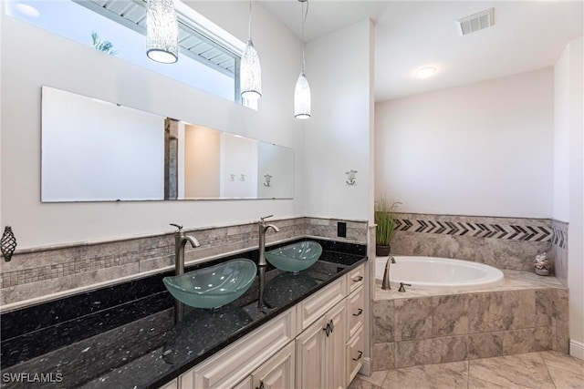 full bath with a sink, visible vents, a garden tub, and double vanity