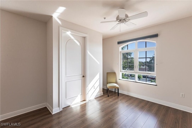 unfurnished room featuring baseboards, dark wood-type flooring, and a ceiling fan