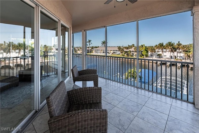 sunroom featuring a residential view, a water view, and a ceiling fan