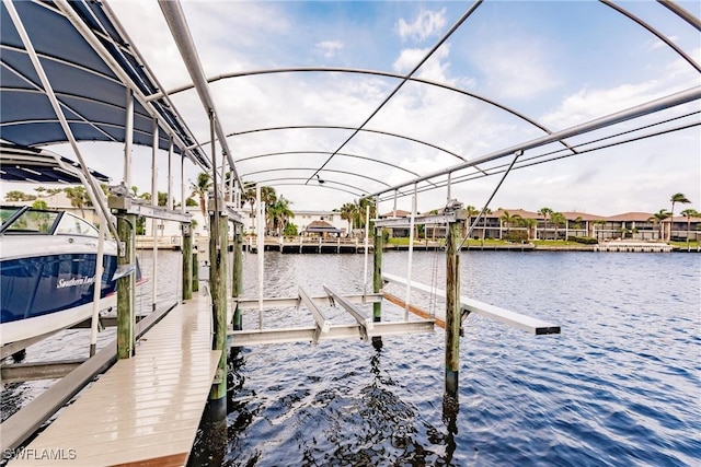 view of dock with a water view, a residential view, and boat lift