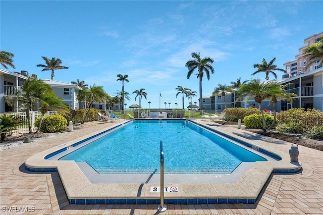 community pool with a patio and fence