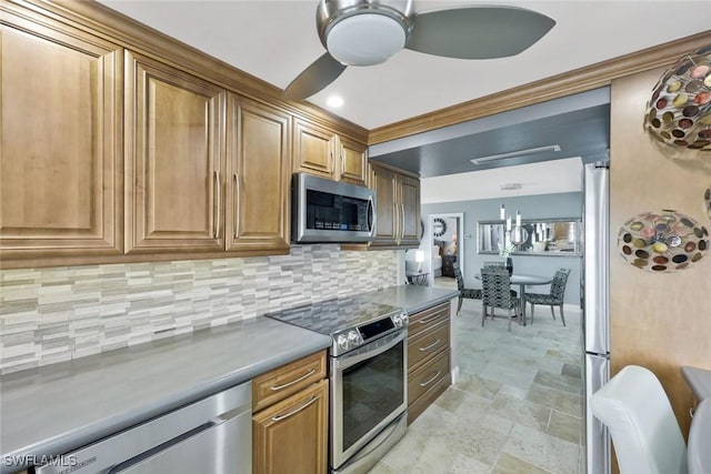 kitchen with ceiling fan, decorative backsplash, stainless steel appliances, stone finish floor, and brown cabinets