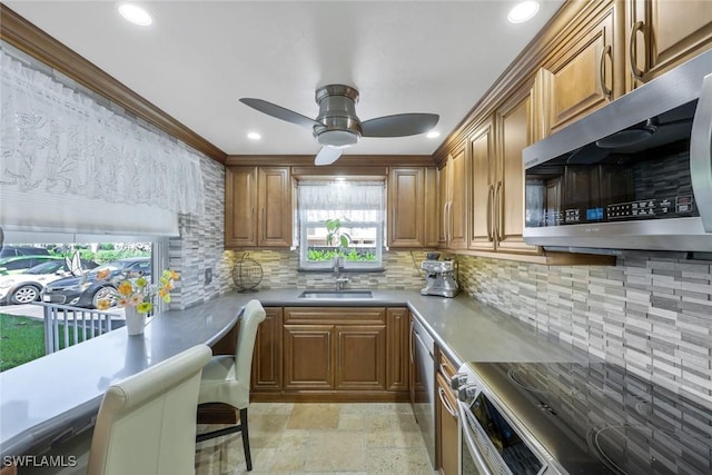 kitchen with a sink, stainless steel appliances, stone tile flooring, and brown cabinetry