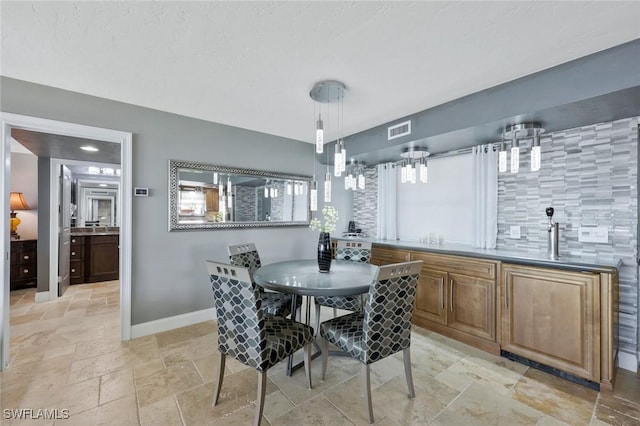 dining room featuring stone tile floors, baseboards, and visible vents