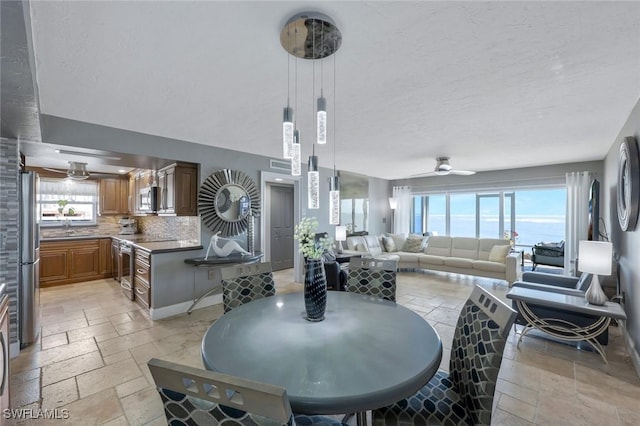 dining area featuring a wealth of natural light, baseboards, stone tile flooring, and a ceiling fan