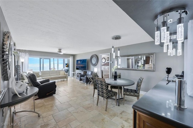 dining area with stone tile floors, baseboards, a textured ceiling, and a ceiling fan