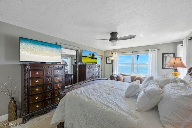 bedroom featuring a ceiling fan, baseboards, and a textured ceiling