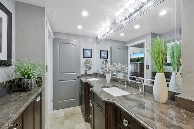 bathroom featuring a sink, stone finish flooring, recessed lighting, and double vanity