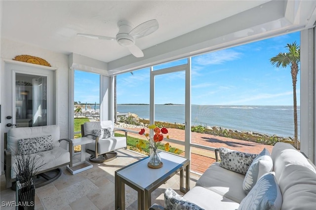 sunroom / solarium with a ceiling fan and a water view