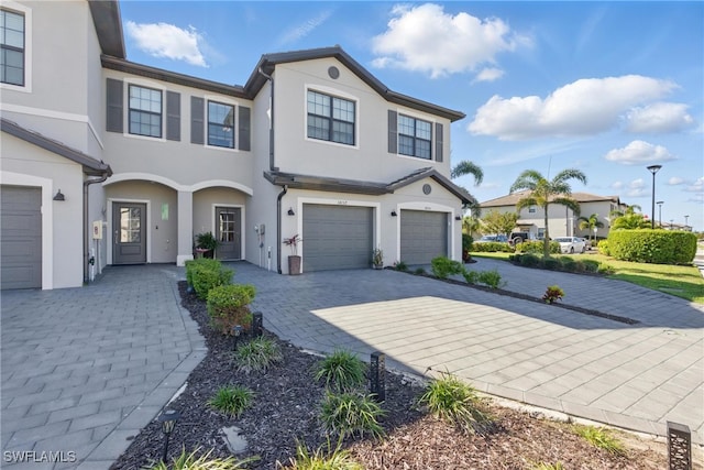 view of front of property featuring stucco siding, decorative driveway, and a garage