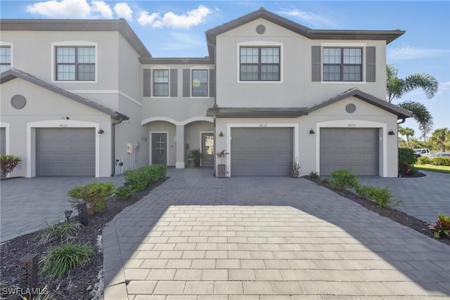 view of front of house featuring stucco siding, an attached garage, and decorative driveway