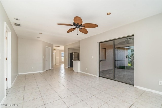 spare room featuring light tile patterned flooring, visible vents, a ceiling fan, and baseboards