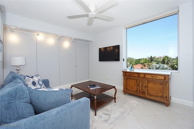 living area with light tile patterned floors, baseboards, and a ceiling fan