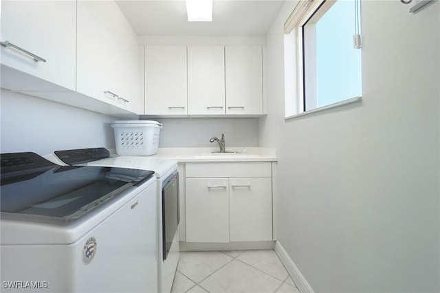 laundry area with washing machine and clothes dryer, baseboards, light tile patterned floors, cabinet space, and a sink