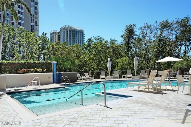 pool with fence, a city view, and a patio area