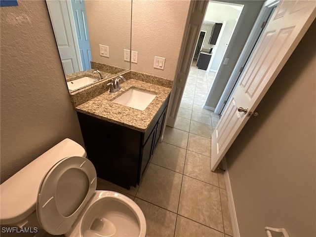 bathroom with tile patterned flooring, vanity, toilet, and a textured wall