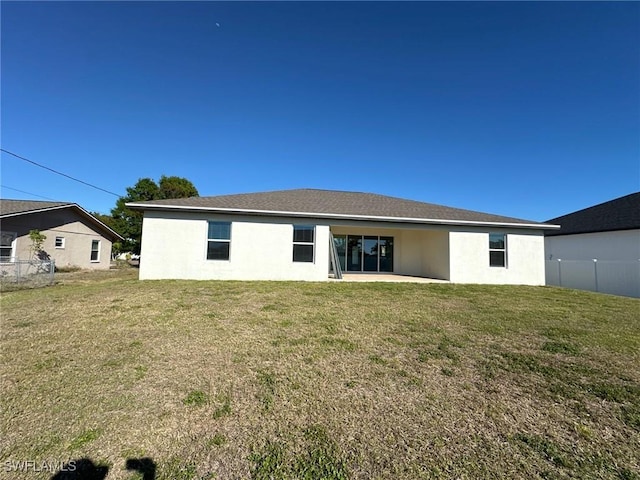 back of house with stucco siding, a lawn, a patio area, and fence