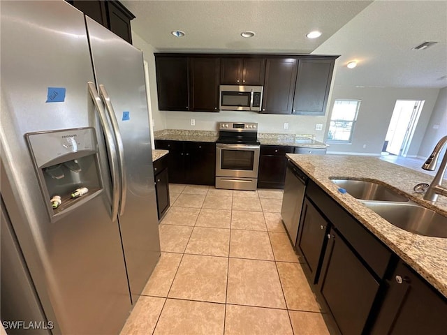 kitchen featuring light stone counters, light tile patterned flooring, recessed lighting, a sink, and stainless steel appliances