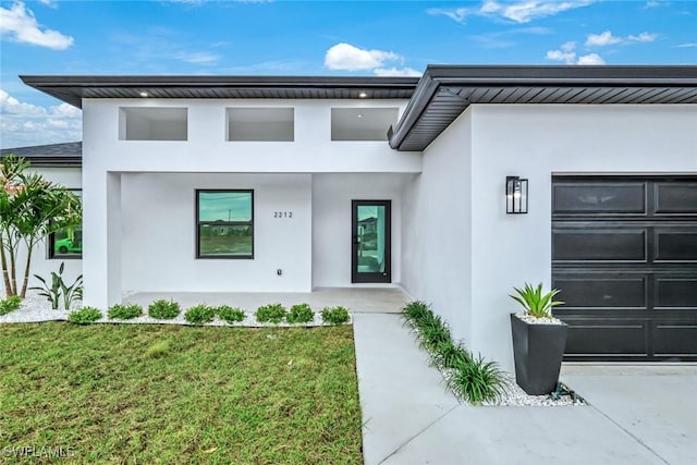 view of front of property with stucco siding, driveway, an attached garage, and a front lawn