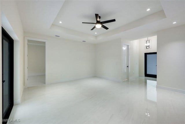 unfurnished room with a tray ceiling, recessed lighting, and baseboards