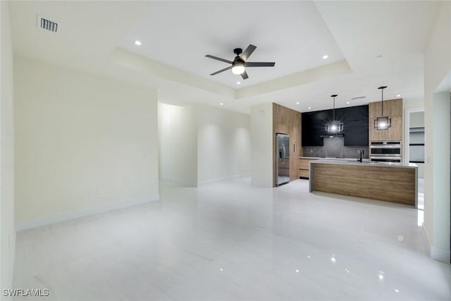 kitchen with modern cabinets, a sink, open floor plan, stainless steel fridge with ice dispenser, and a raised ceiling