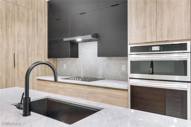 kitchen with a sink, black electric stovetop, stainless steel double oven, and modern cabinets