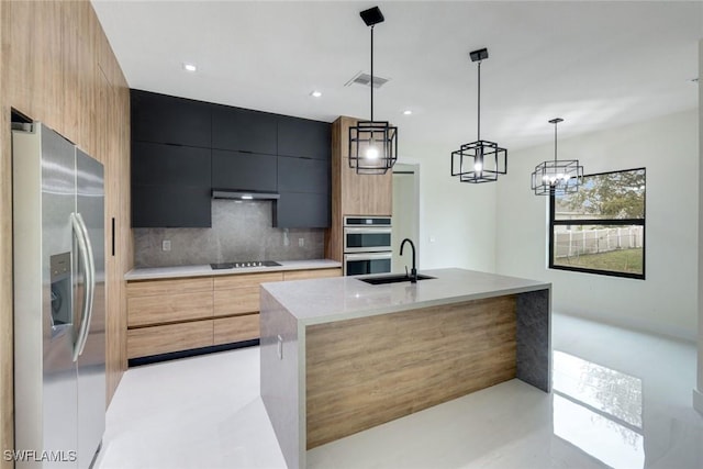 kitchen featuring modern cabinets, a sink, under cabinet range hood, stainless steel appliances, and decorative backsplash