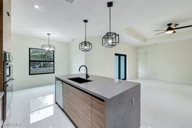 kitchen featuring open floor plan, a tray ceiling, appliances with stainless steel finishes, modern cabinets, and a sink