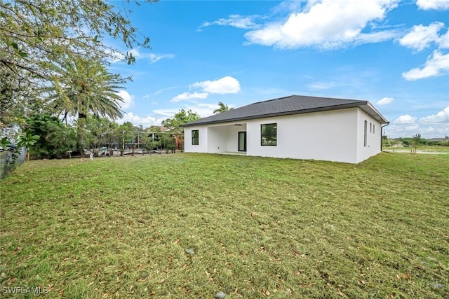 rear view of house with a lawn and stucco siding