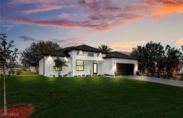 prairie-style home featuring concrete driveway, a lawn, and a garage