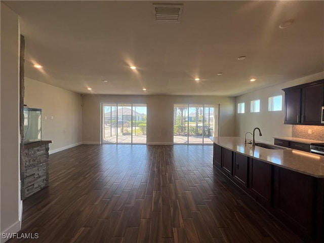 kitchen featuring visible vents, dark brown cabinets, a sink, open floor plan, and dark wood-style flooring