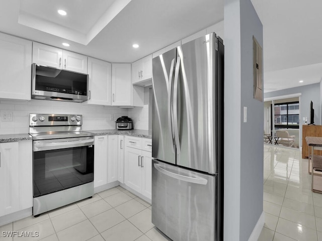 kitchen featuring decorative backsplash, light stone countertops, white cabinetry, and appliances with stainless steel finishes