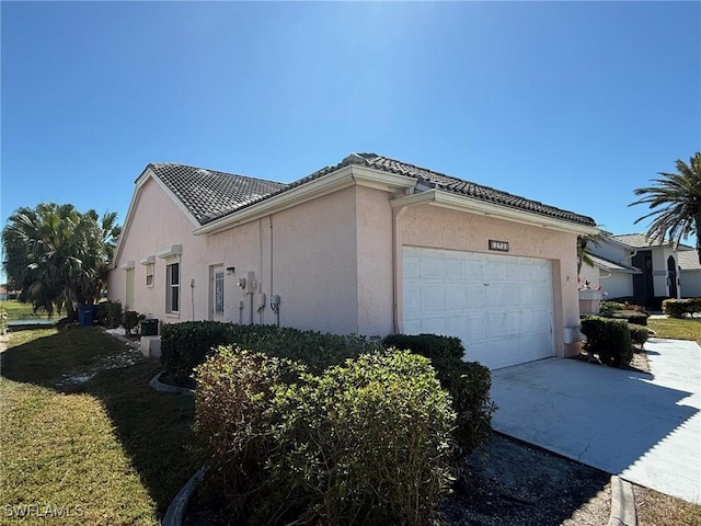 view of home's exterior with stucco siding, a garage, concrete driveway, and a tile roof