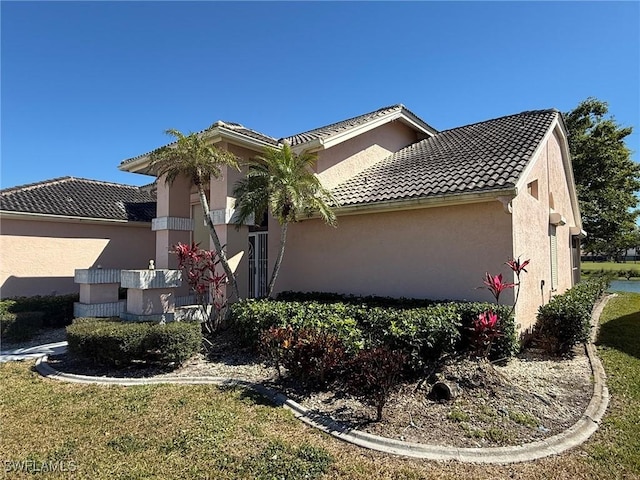 view of side of home featuring stucco siding and a tile roof