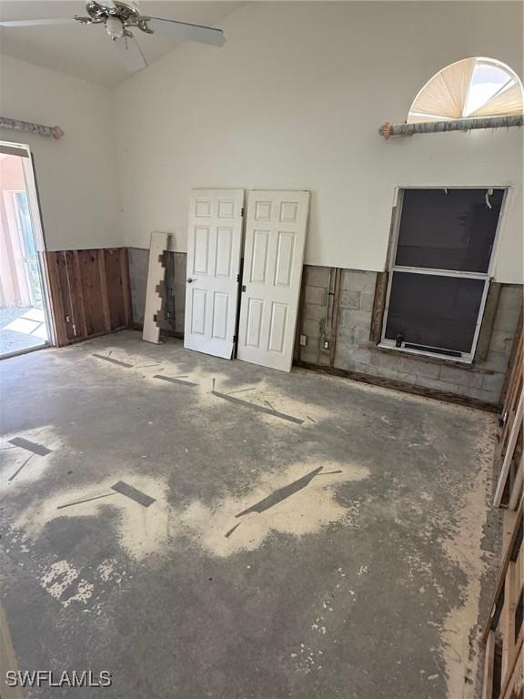 unfurnished living room featuring high vaulted ceiling and concrete floors