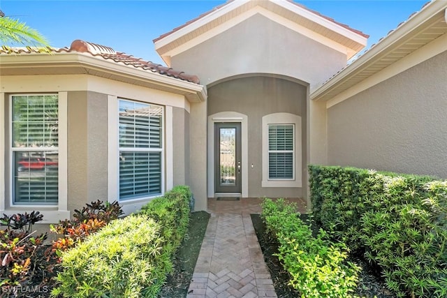 entrance to property with stucco siding and a tiled roof