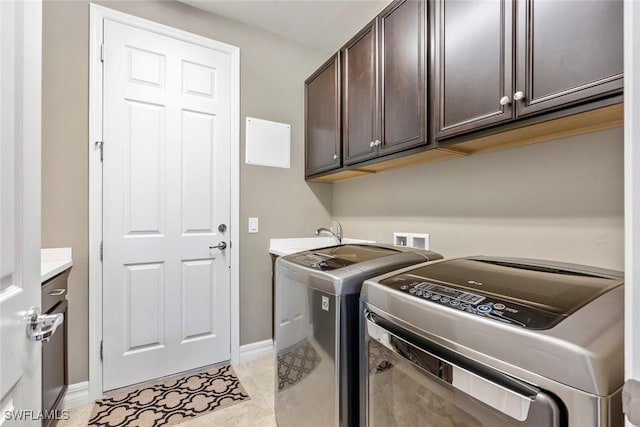 laundry room featuring light tile patterned floors, baseboards, washing machine and clothes dryer, cabinet space, and a sink