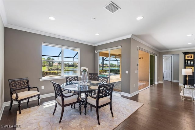 dining space featuring visible vents, crown molding, baseboards, a sunroom, and wood finished floors