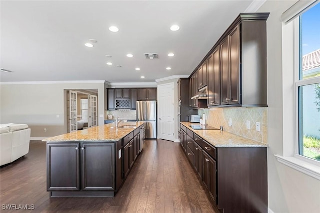 kitchen featuring under cabinet range hood, dark brown cabinetry, freestanding refrigerator, black electric cooktop, and a sink