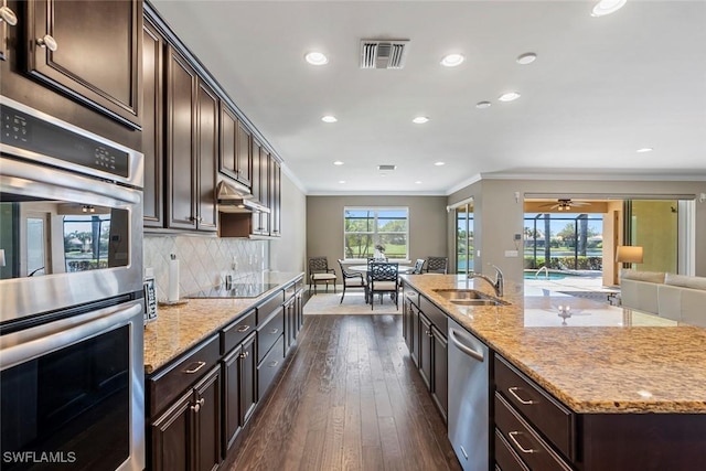 kitchen featuring visible vents, a sink, dark brown cabinetry, appliances with stainless steel finishes, and tasteful backsplash