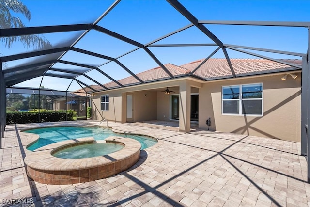 view of pool with glass enclosure, a pool with connected hot tub, ceiling fan, and a patio area