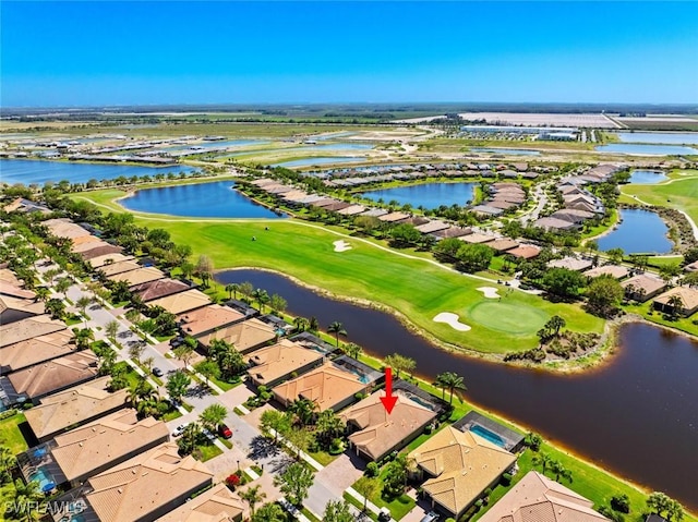 drone / aerial view with view of golf course, a residential view, and a water view