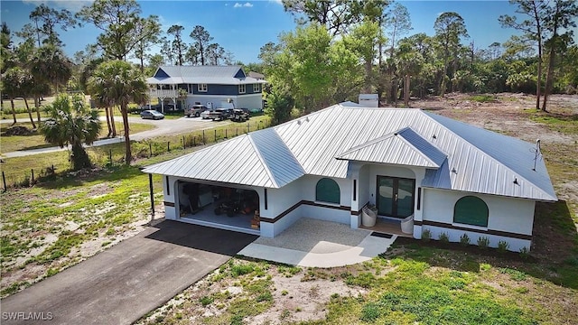 view of front of house with metal roof, a garage, stucco siding, and aphalt driveway