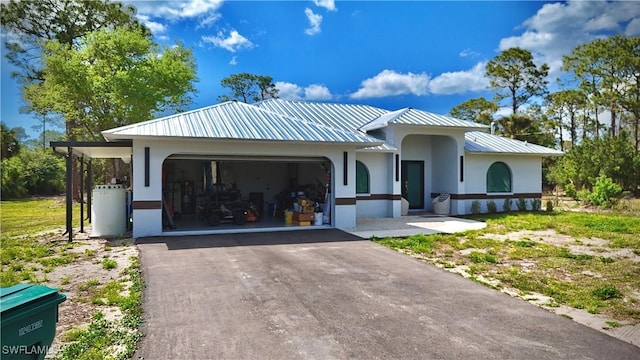 view of front of house featuring aphalt driveway, an attached garage, metal roof, and stucco siding