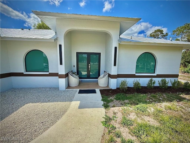 property entrance featuring stucco siding and french doors
