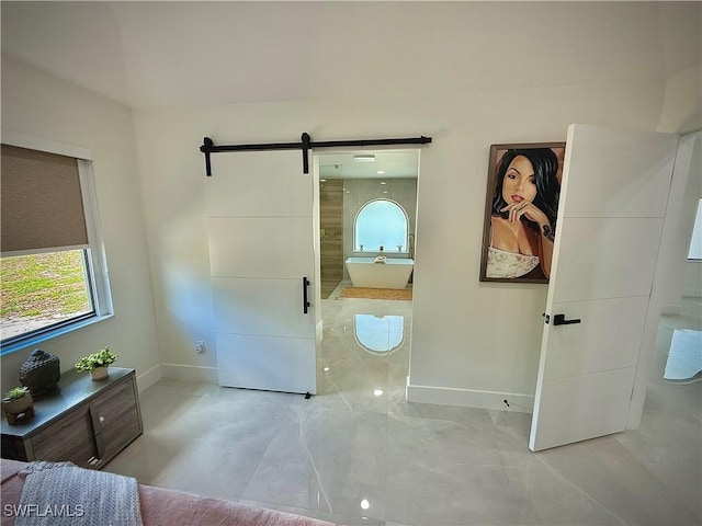 bedroom with a barn door and baseboards