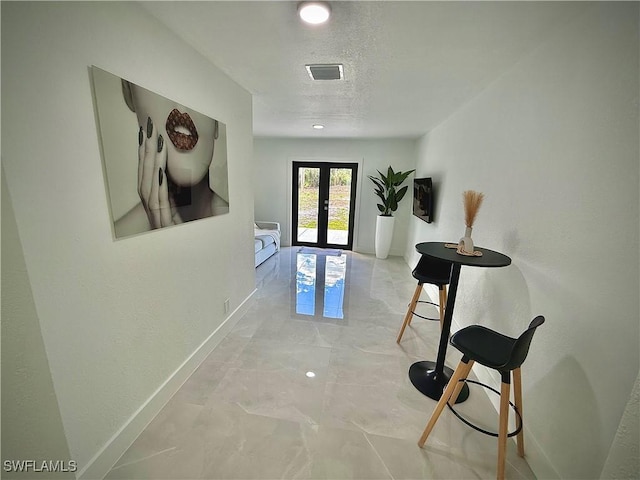 hallway with visible vents, baseboards, french doors, a textured ceiling, and marble finish floor