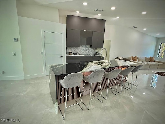 kitchen featuring a kitchen bar, visible vents, modern cabinets, gray cabinetry, and a sink