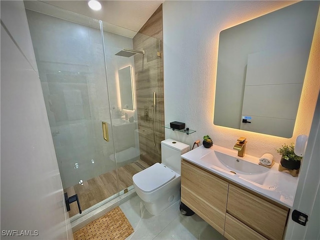 bathroom with vanity, tile patterned flooring, a shower stall, toilet, and a textured wall